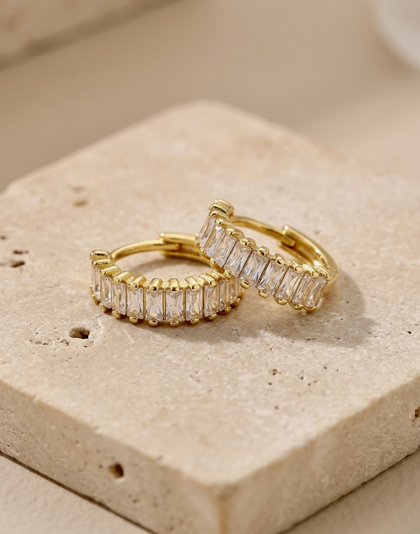 CZ Gold huggie earrings on a tile