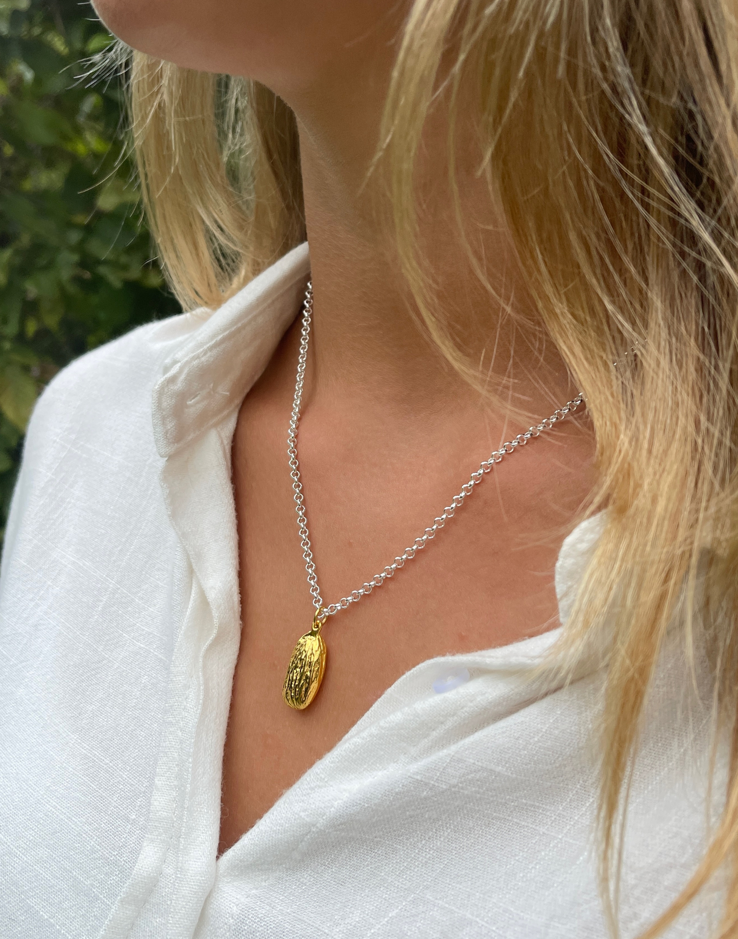 gold almond necklace on silver chain on model