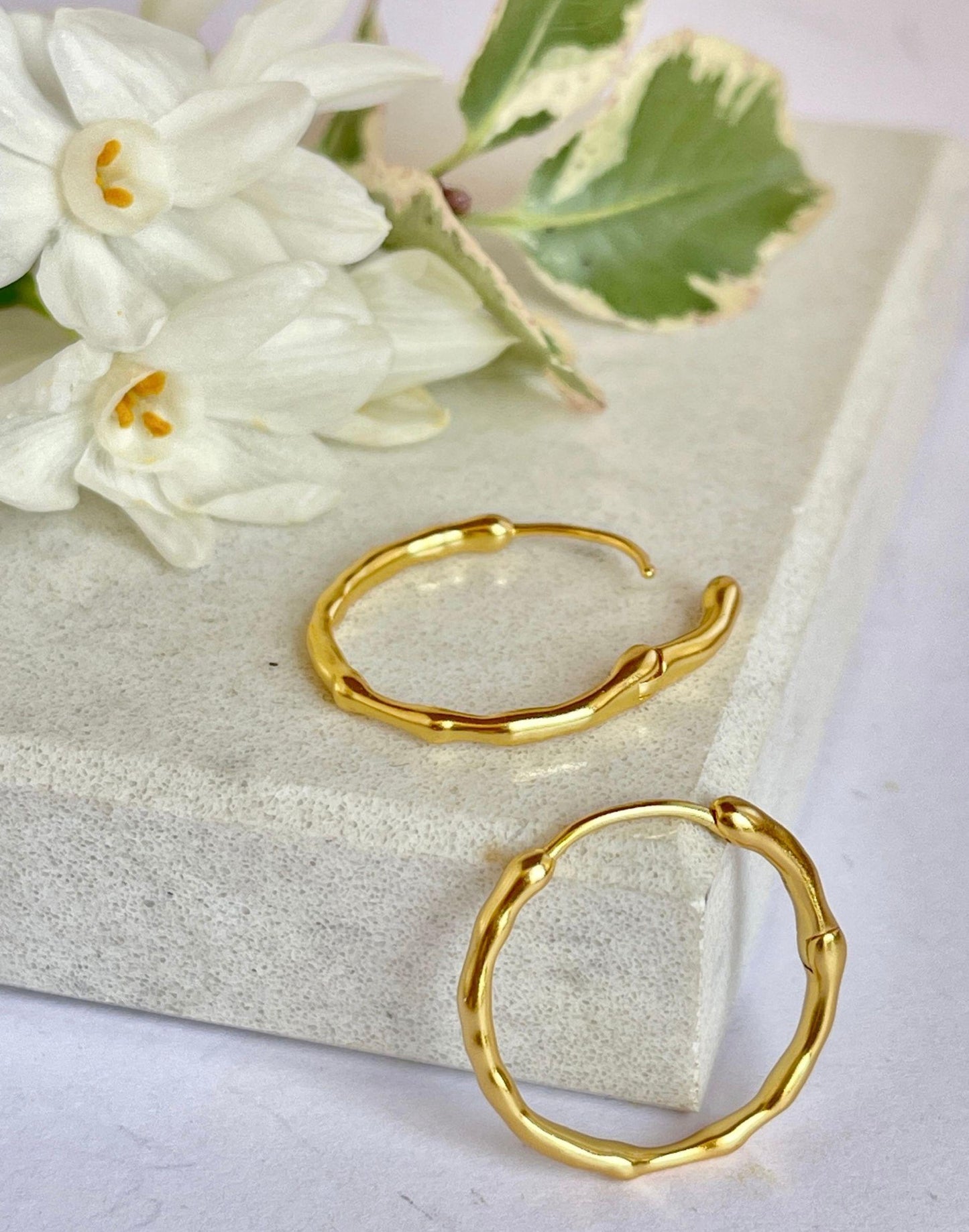 Bold Bamboo Hoop Earrings on a tile with a flower