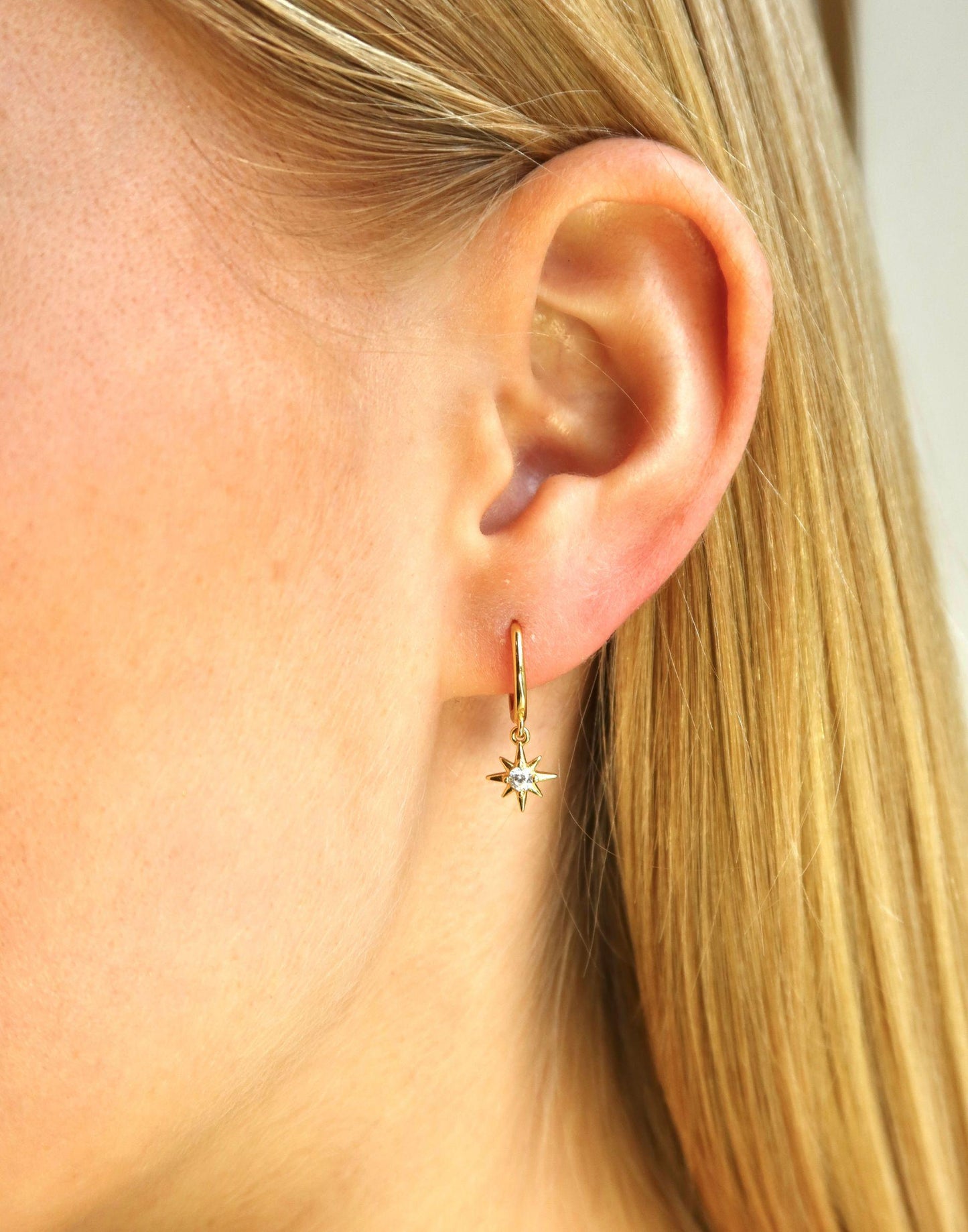 model wears gold CZ star charm huggie earrings