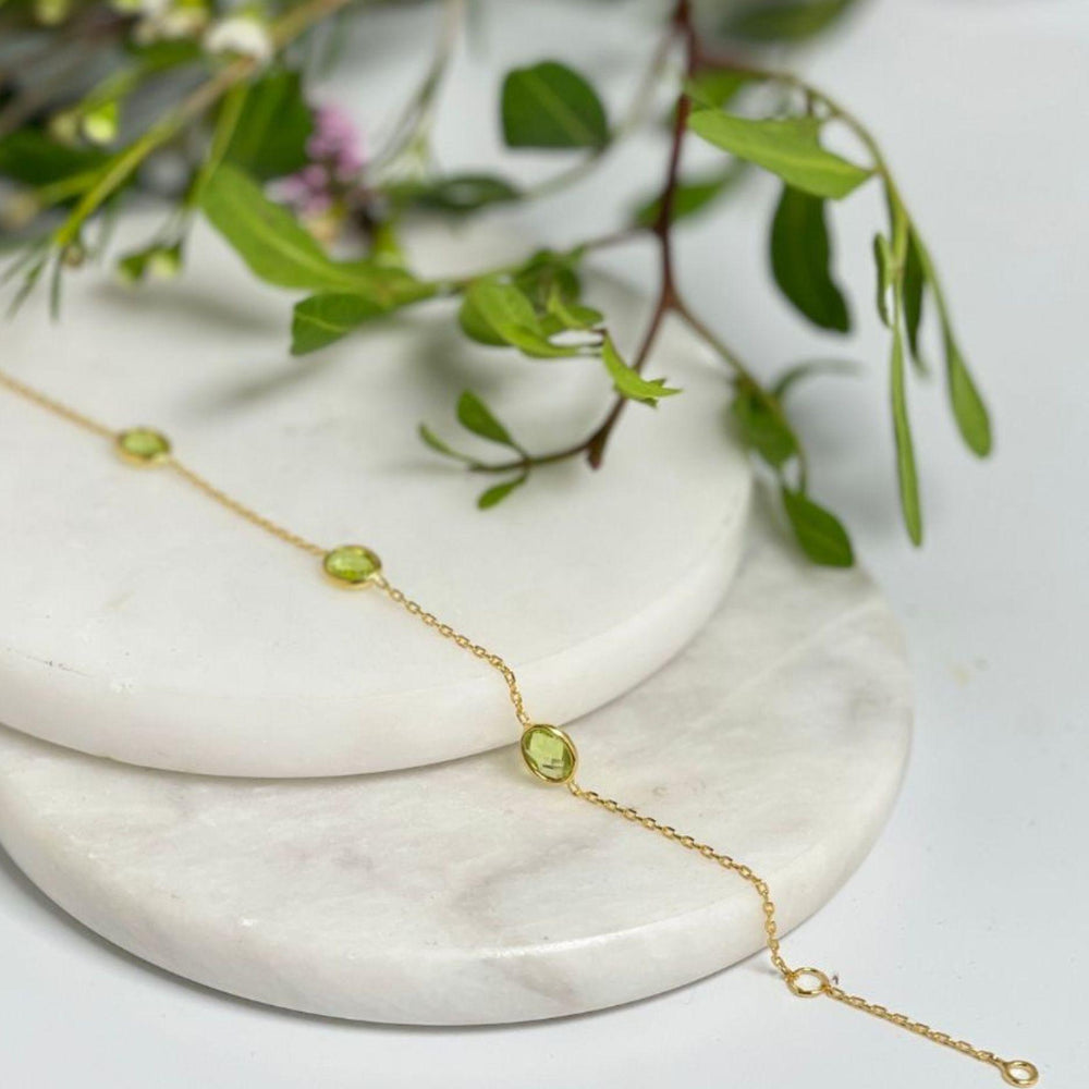 Gold peridot bracelet on tile