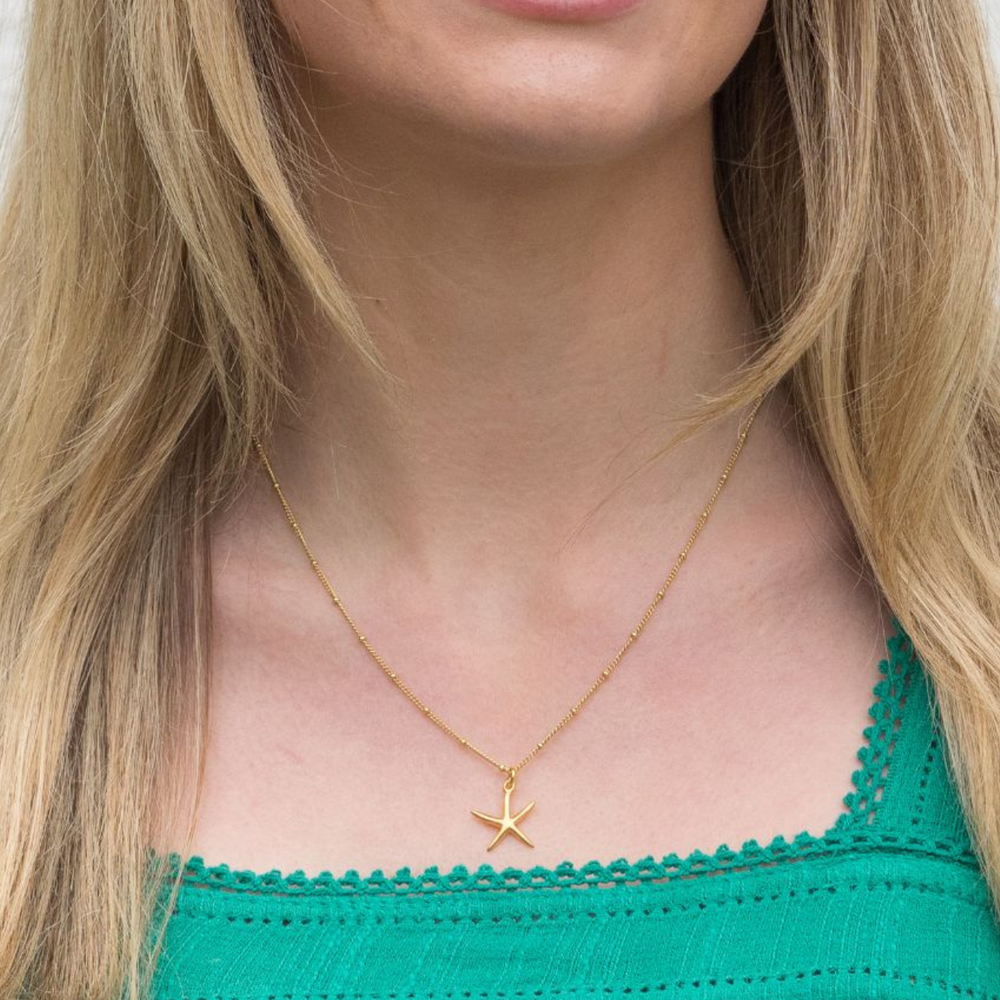 gold starfish necklace on model