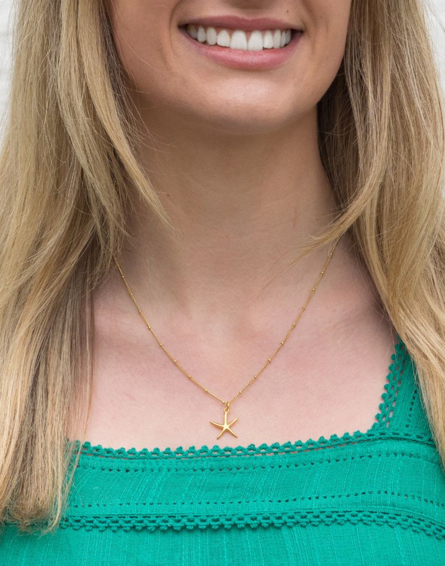 gold starfish necklace on model