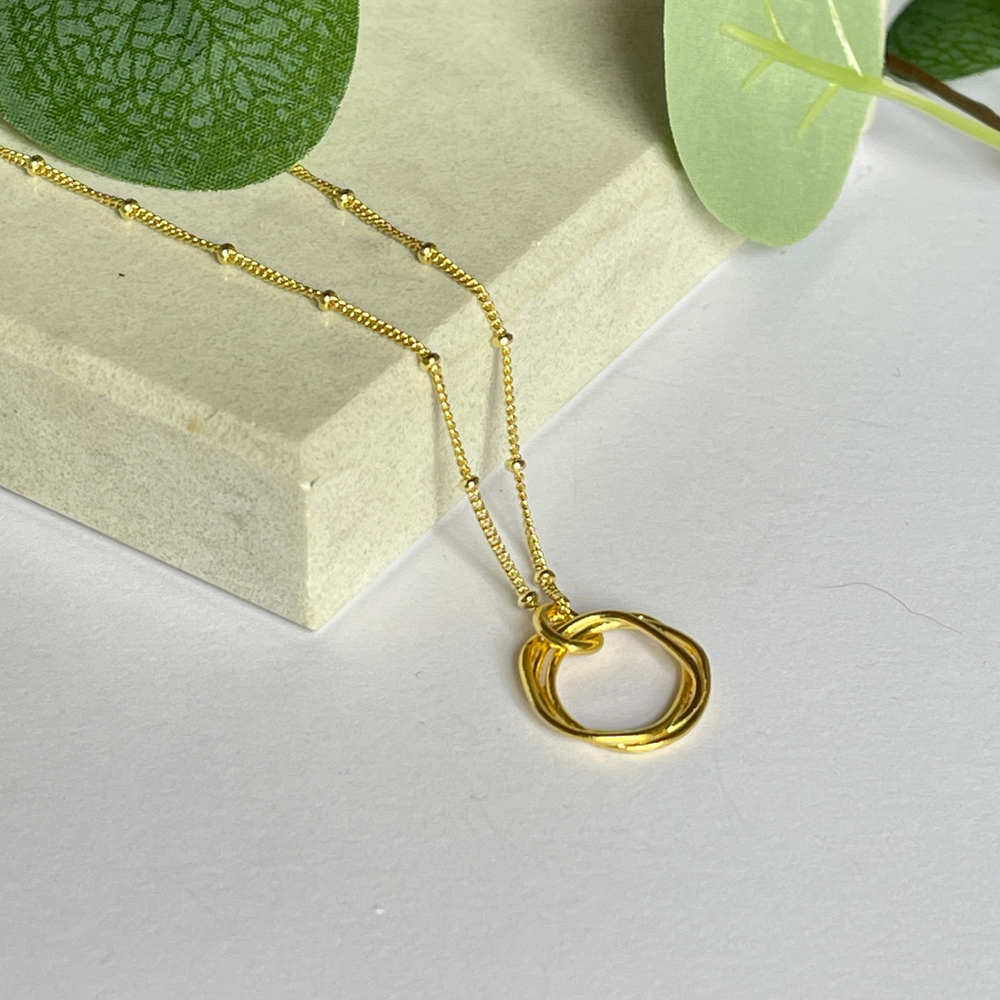 gold twisted circle necklace on tile