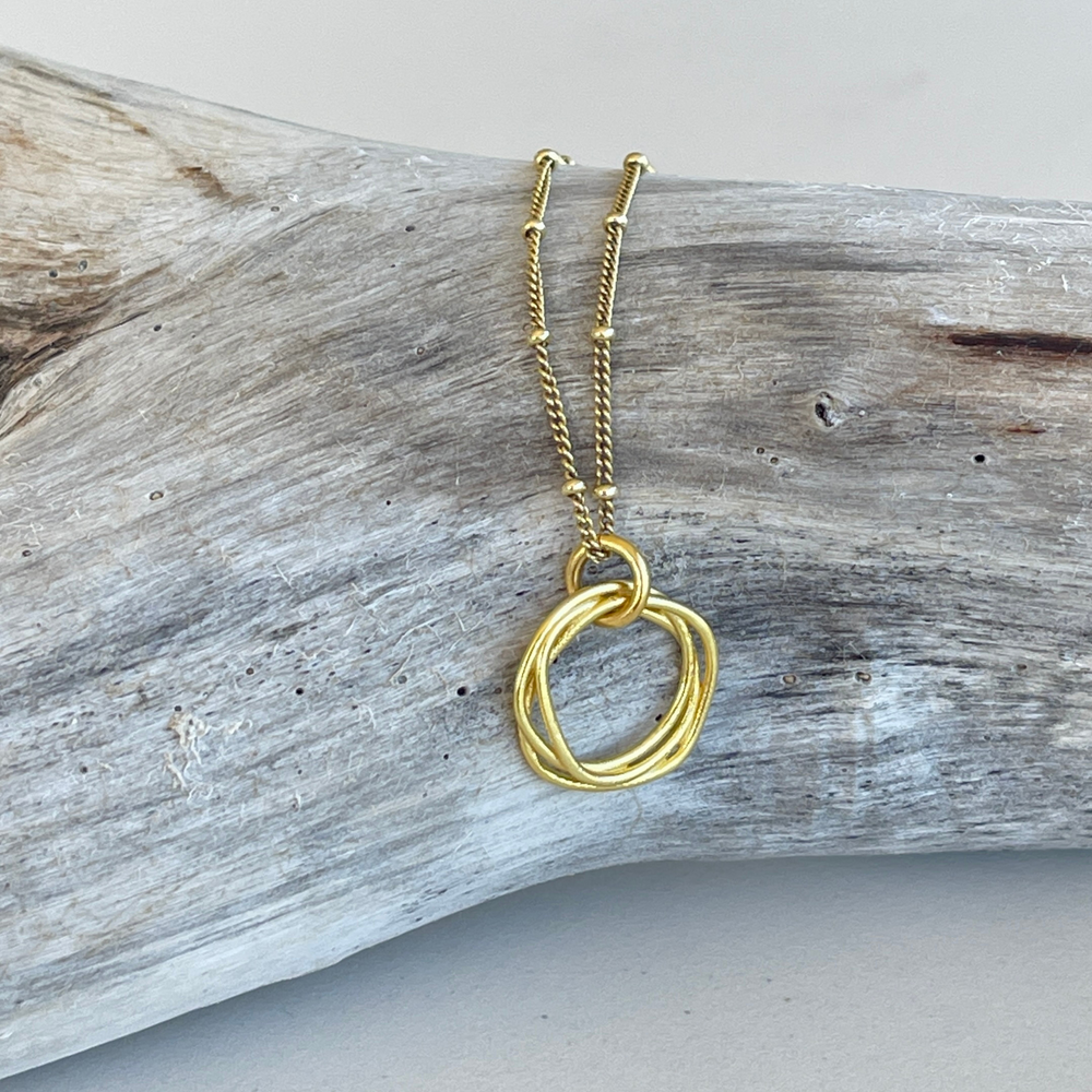 
                  
                    gold twisted circle necklace on branch
                  
                