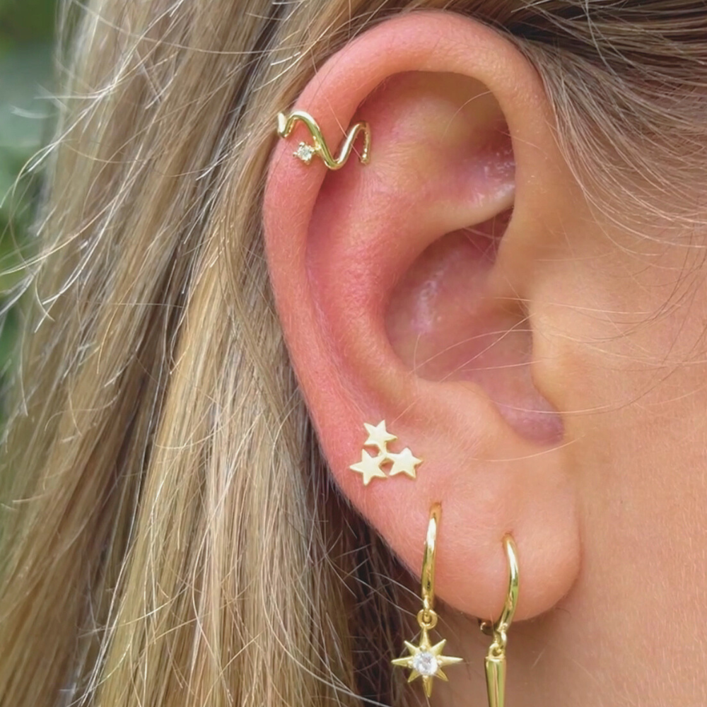 gold wave ear cuff worn with earrings on model