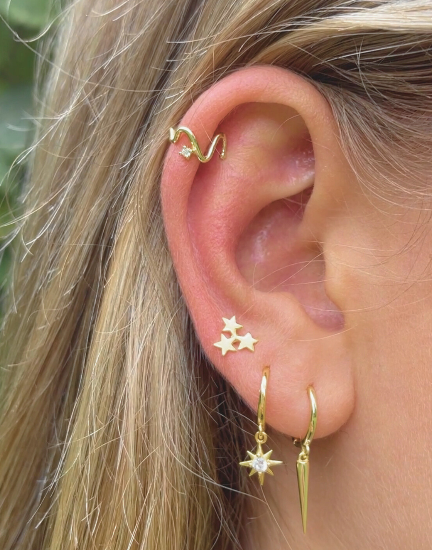 gold wave ear cuff worn with earrings on model