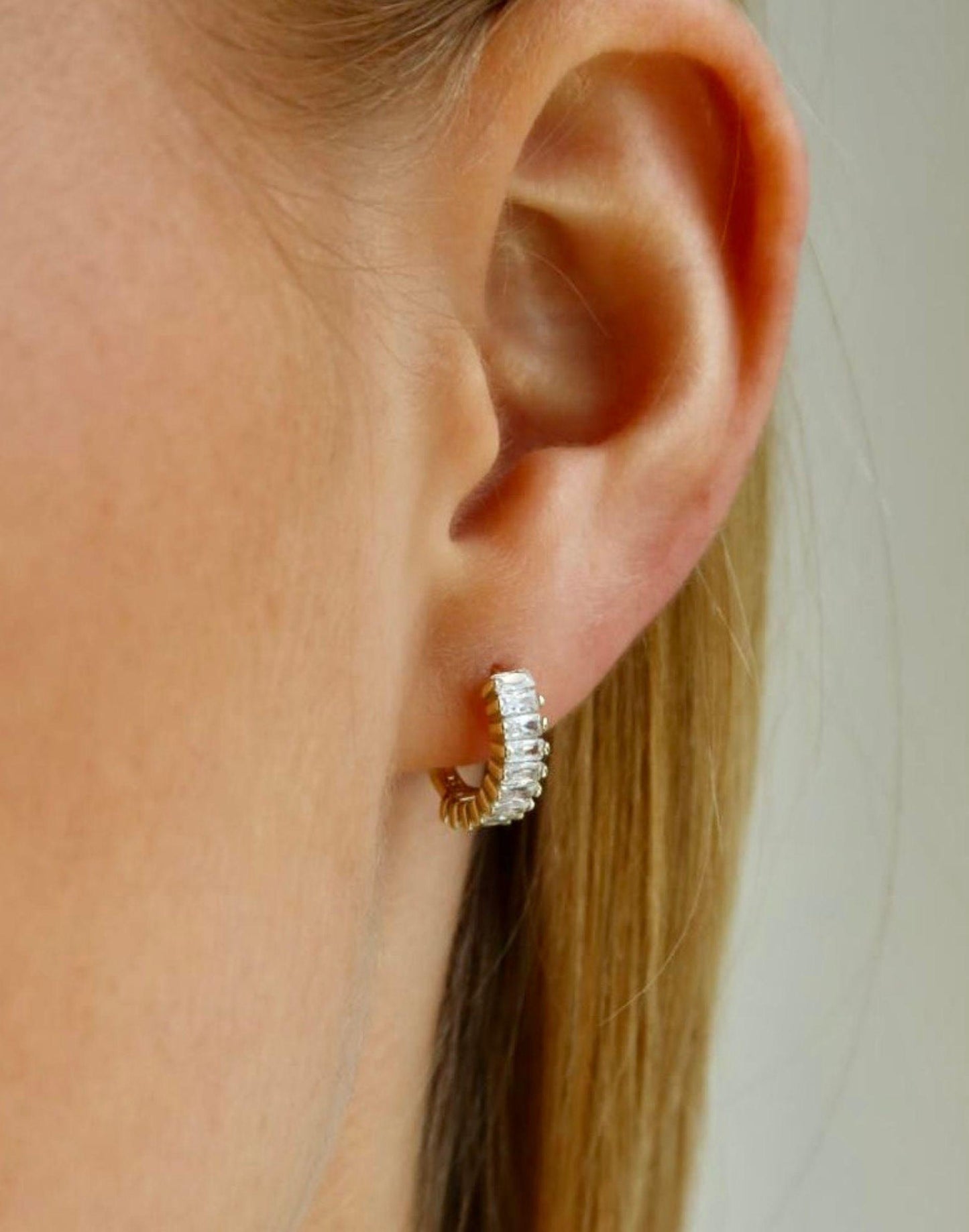 Model wears gold and crystal holiday huggie earrings