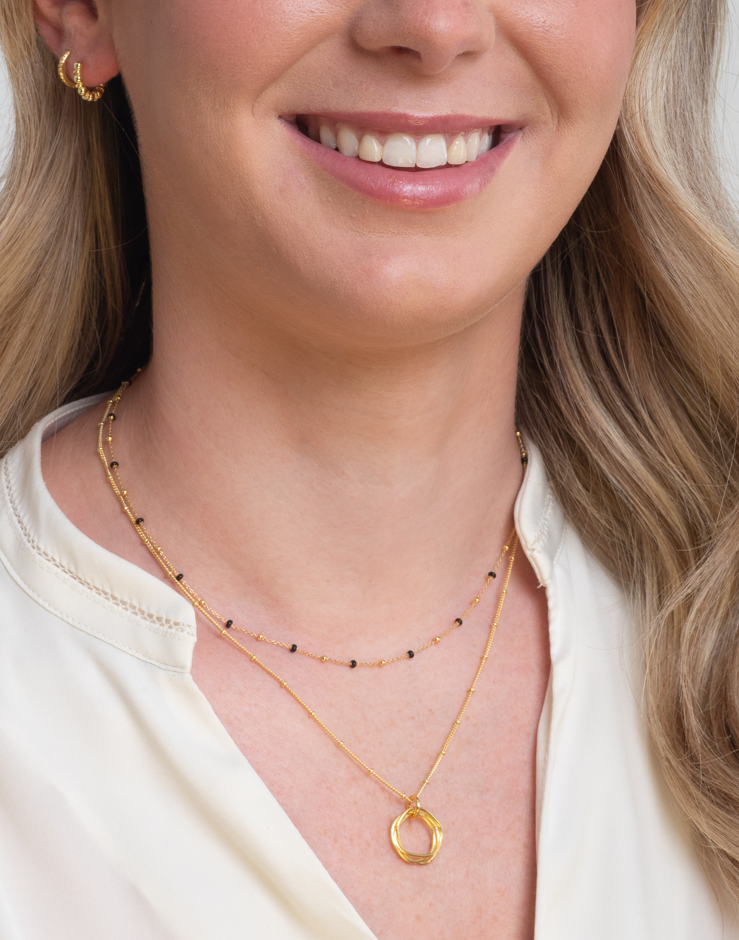 model wears gold black enamel necklace with gold twisted circle necklace