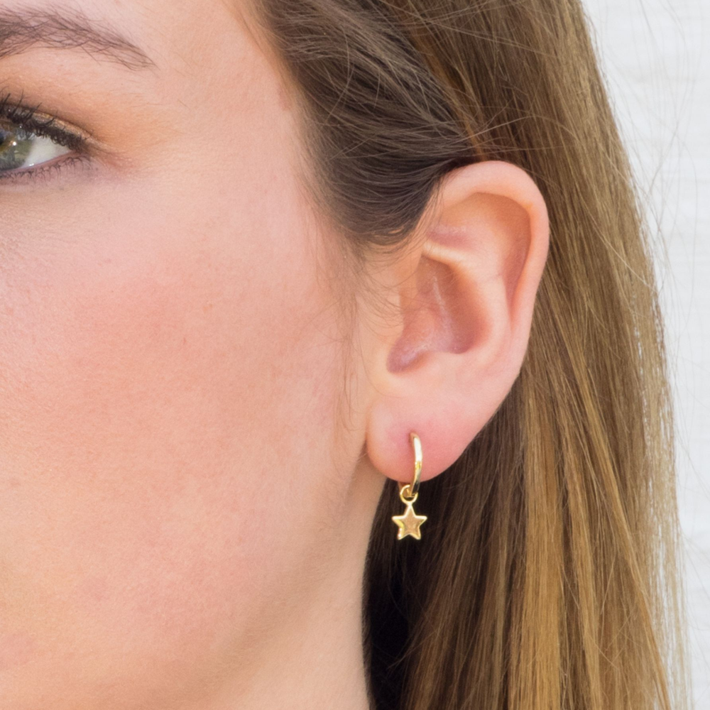 model wears Gold Star charm huggie earrings