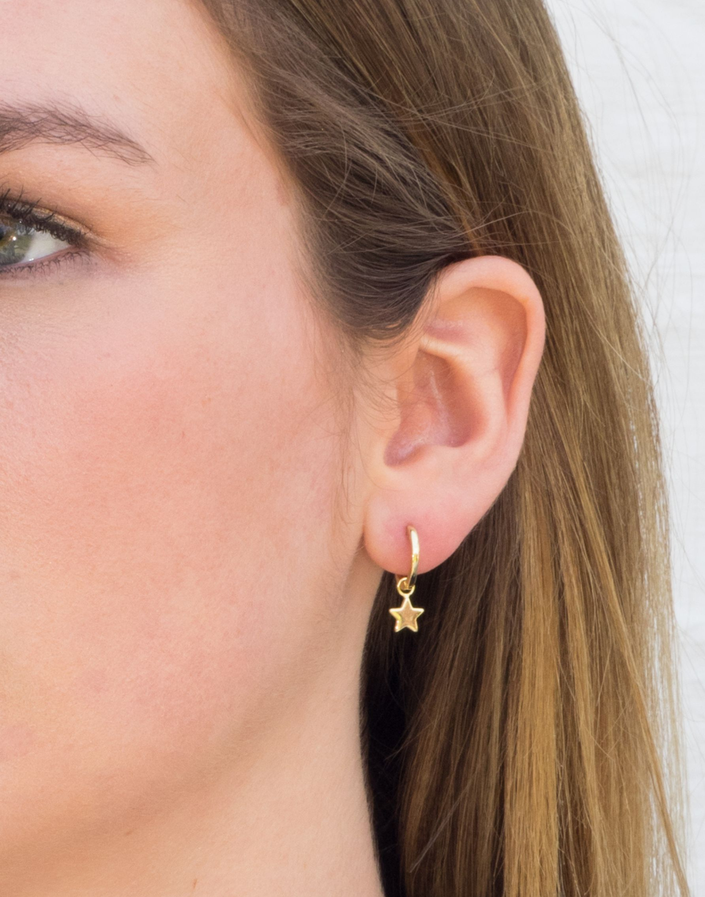 model wears Gold Star charm huggie earrings