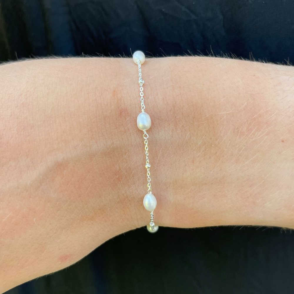 Helena pearl and silver bracelet on a wrist against a dark background