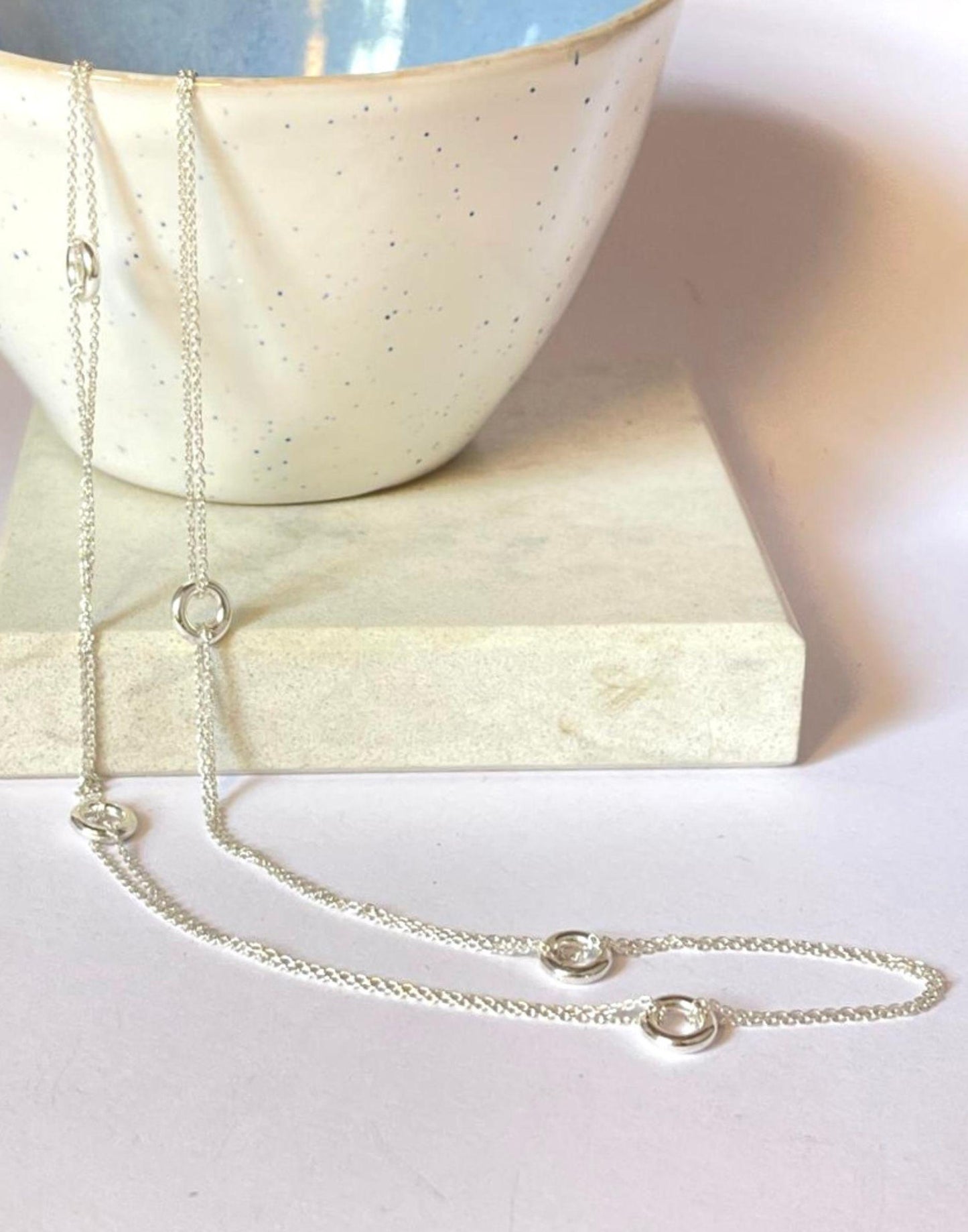 Silver Hoopla Necklace draped over a bowl