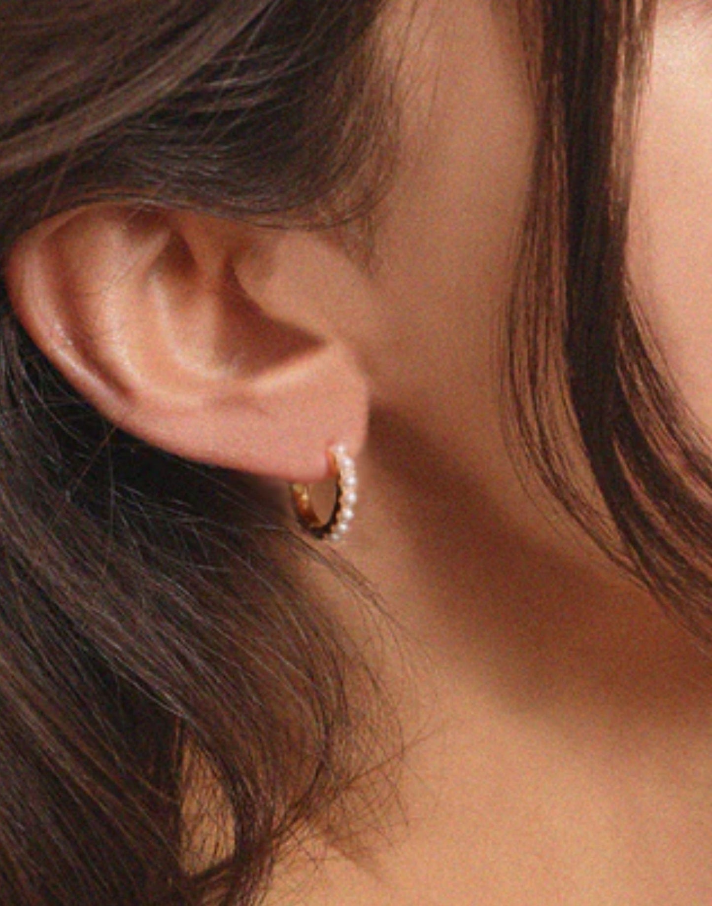 Model wears gold pearl huggie earrings
