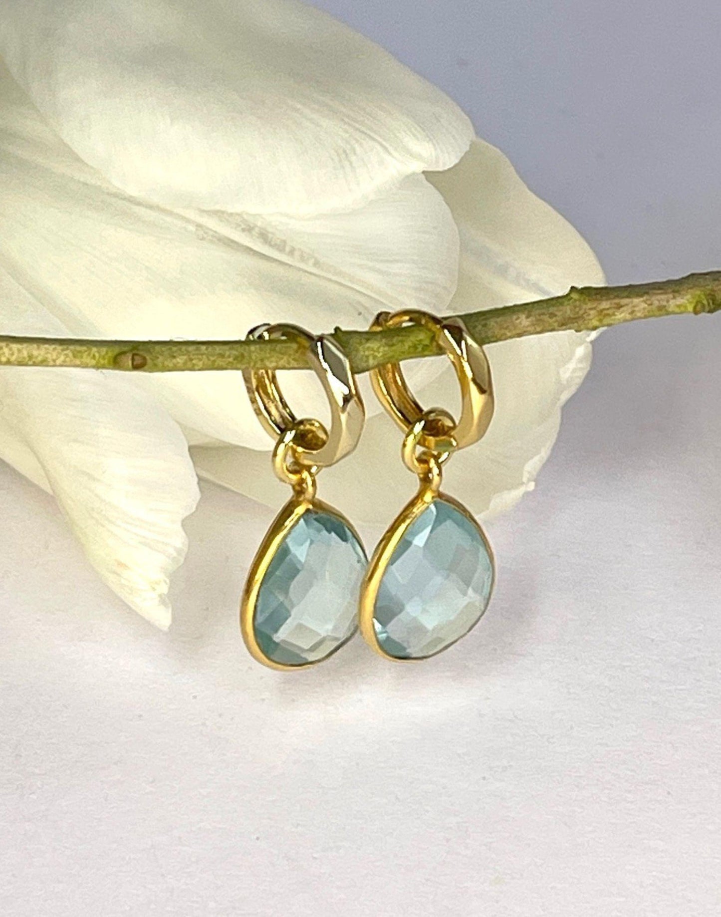 Kiera Blue Topaz Drop Earrings with a flower