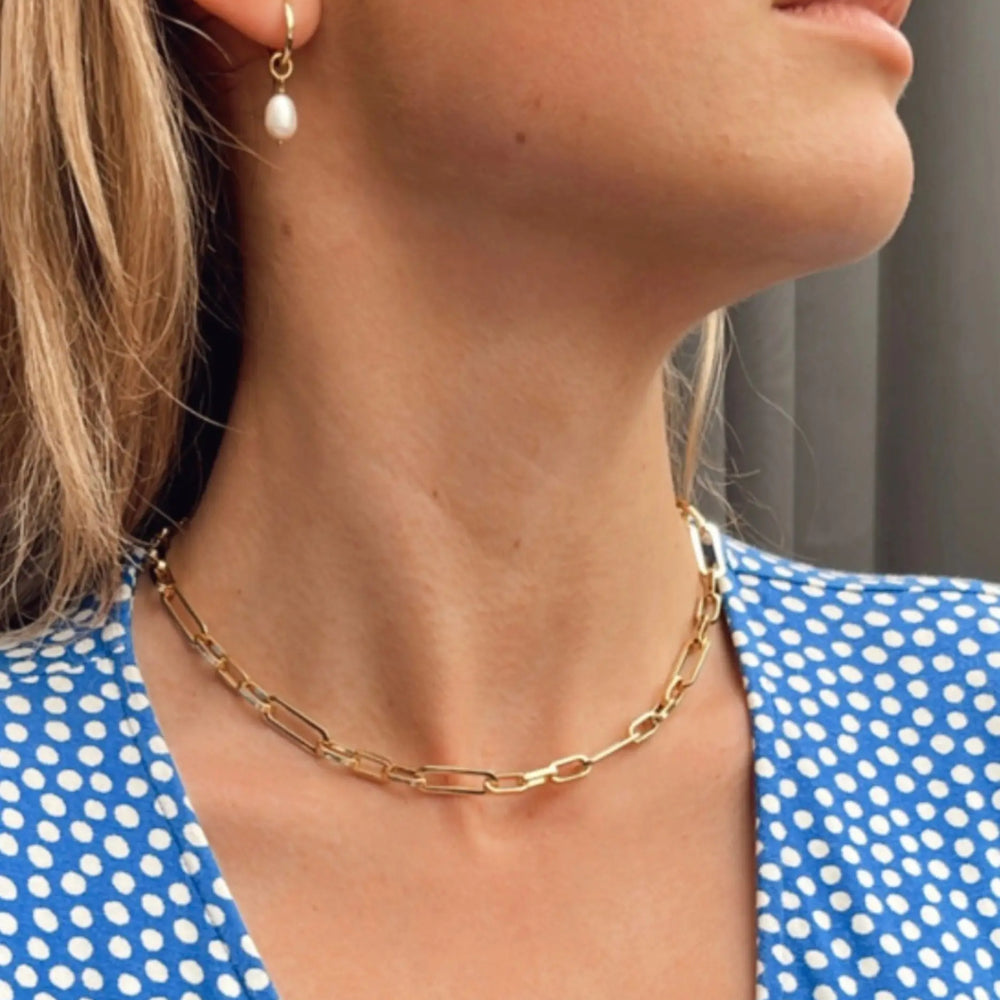 
                  
                    Kitty Gold pearl charm huggies on model in ear
                  
                