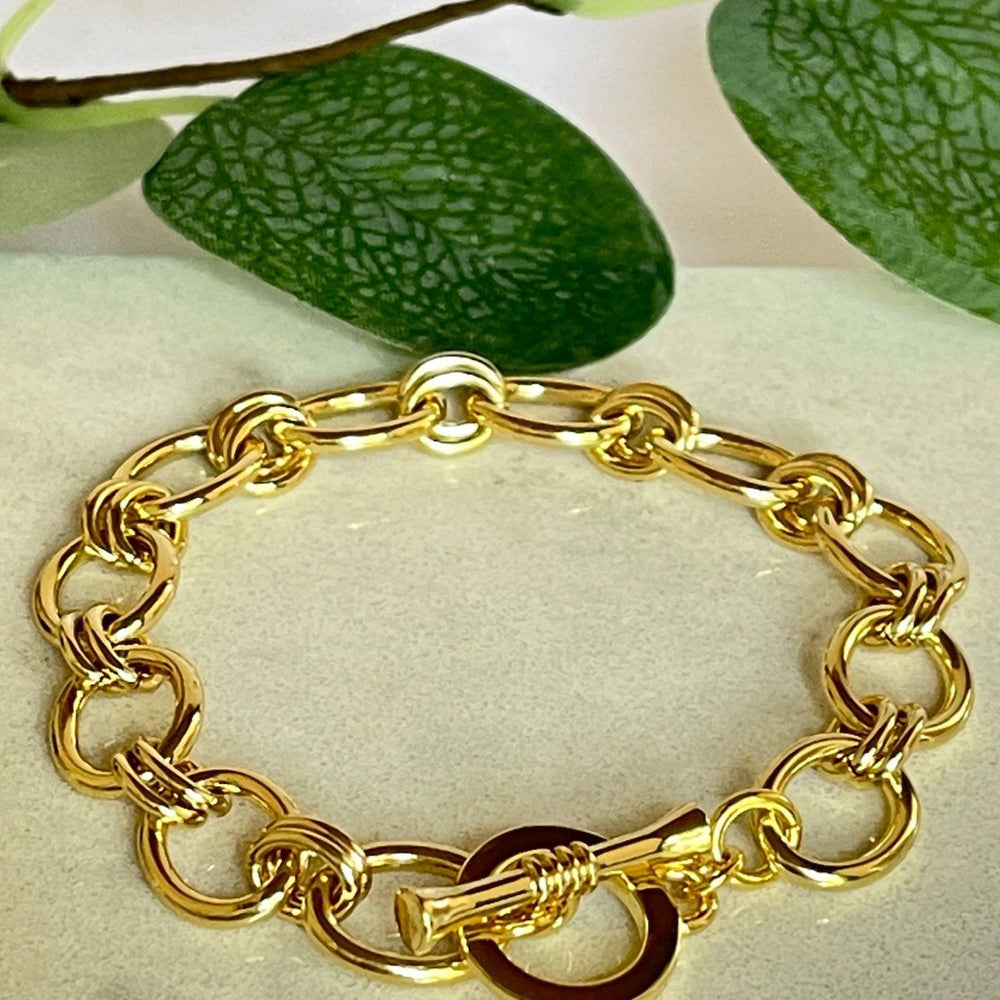 Lizzy gold link bracelet on a tile