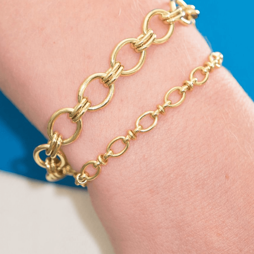 
                  
                    Pippa gold link bracelet with Lizzy gold link bracelet on a wrist with a blue background
                  
                