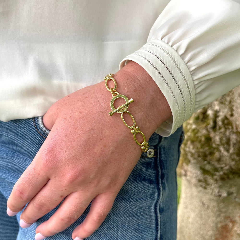 Jessica gold link bracelet on a wrist with a blurred natural background