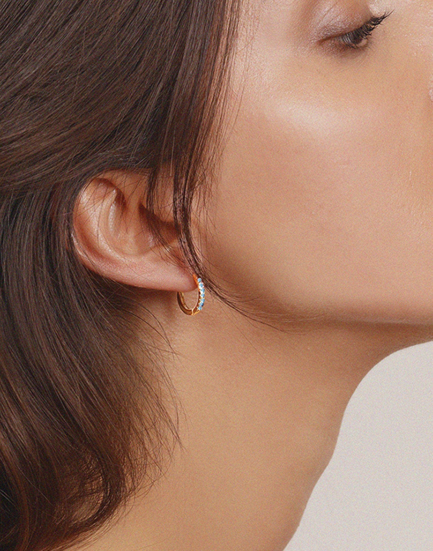 Model wears march birthstone huggie earrings