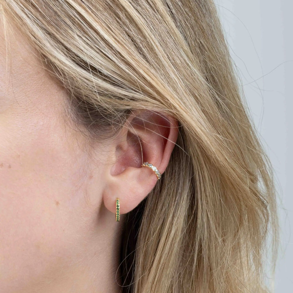 
                  
                    May birthstone gold huggie earrings in ear
                  
                