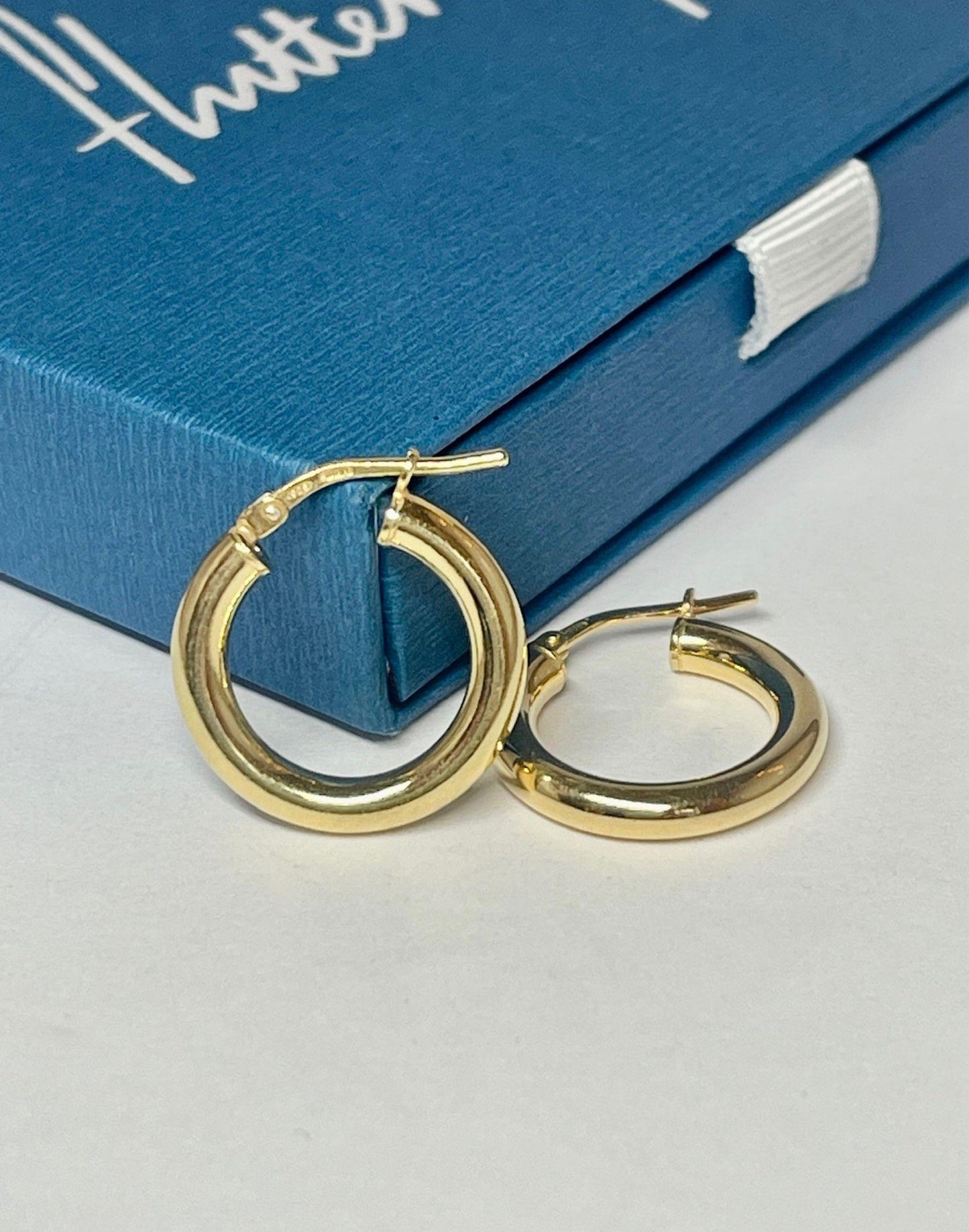 mid sized gold hoop earrings resting on a Flutterby gift box