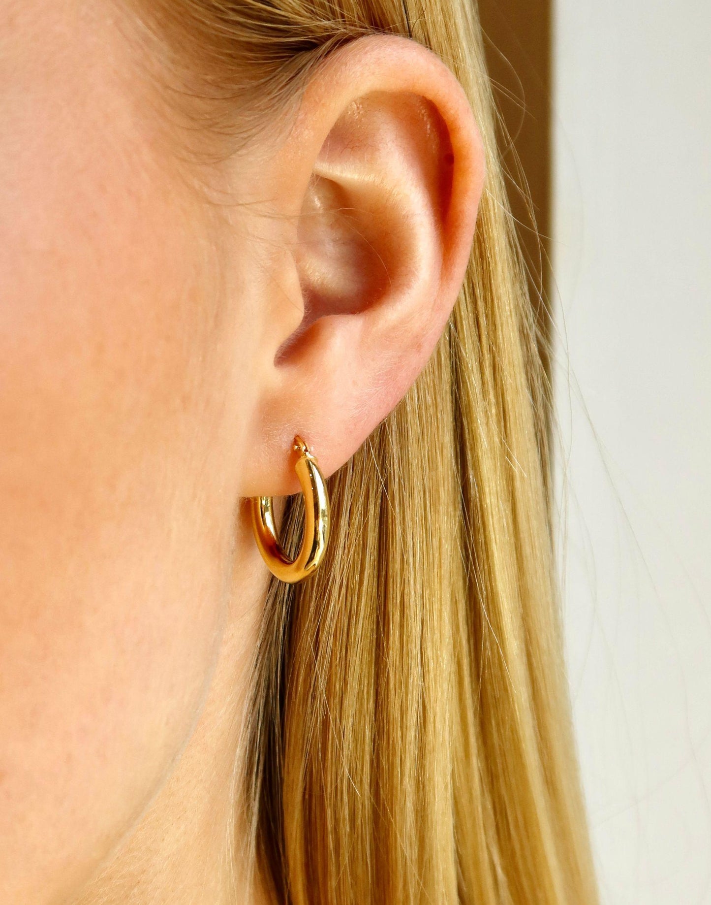 model wears mid-sized gold hoop earrings