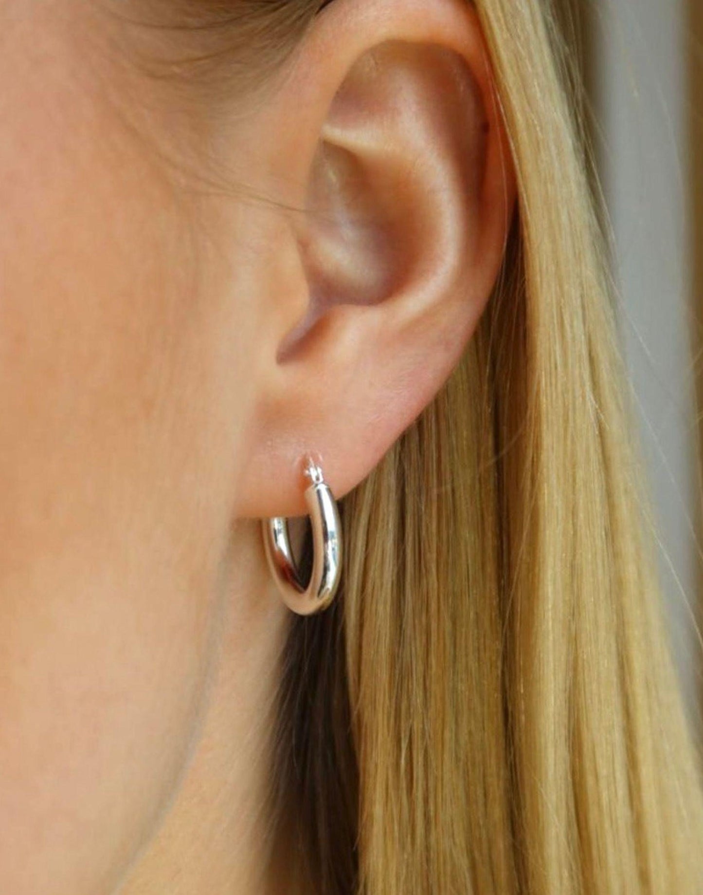 Model wears mid-sized silver hoop earrings