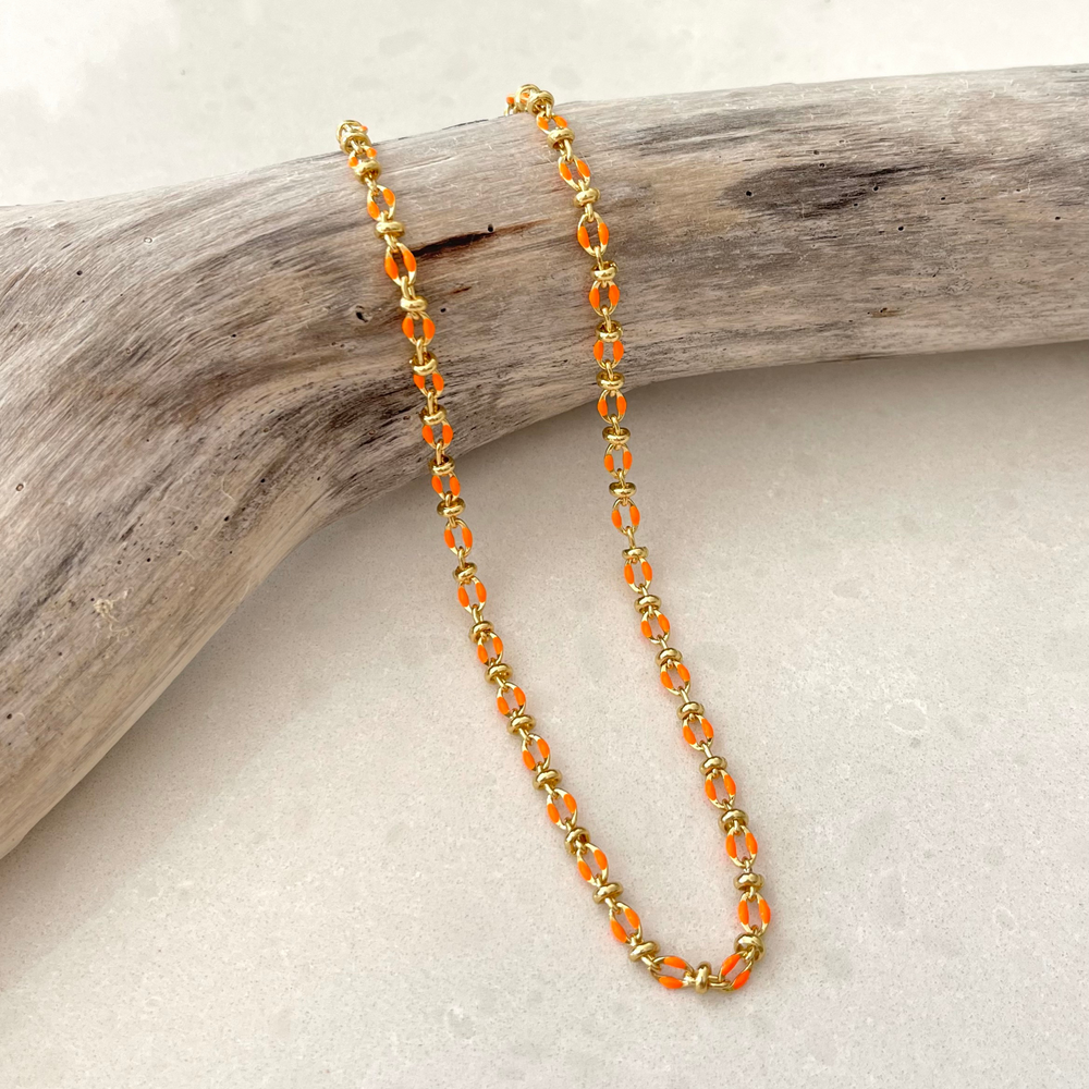 
                  
                    Orange enamel necklace on branch
                  
                