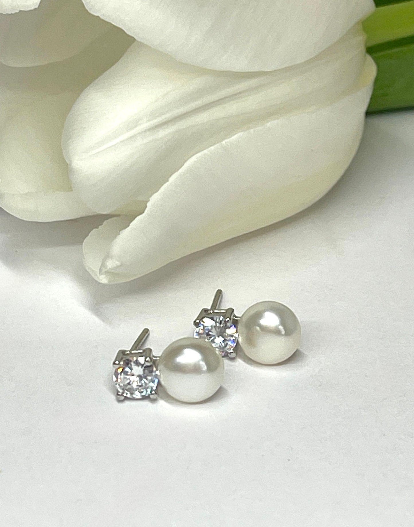 pearl and CZ stud earrings on tile next to tulip