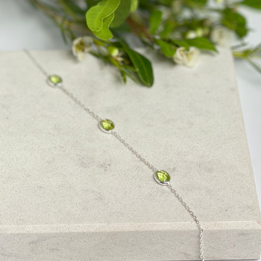 
                  
                    silver peridot bracelet on a tile with flowers
                  
                