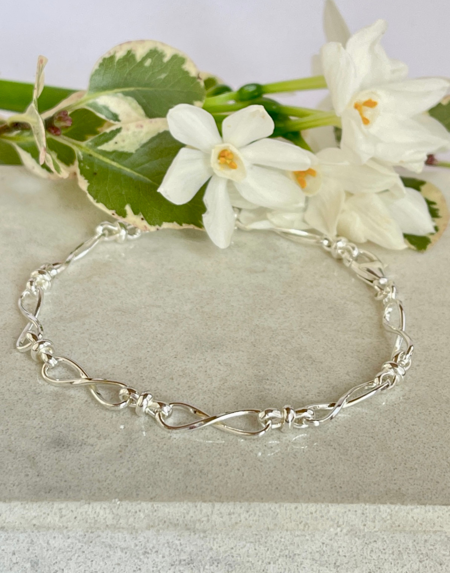Silver infinity bracelet on a tile