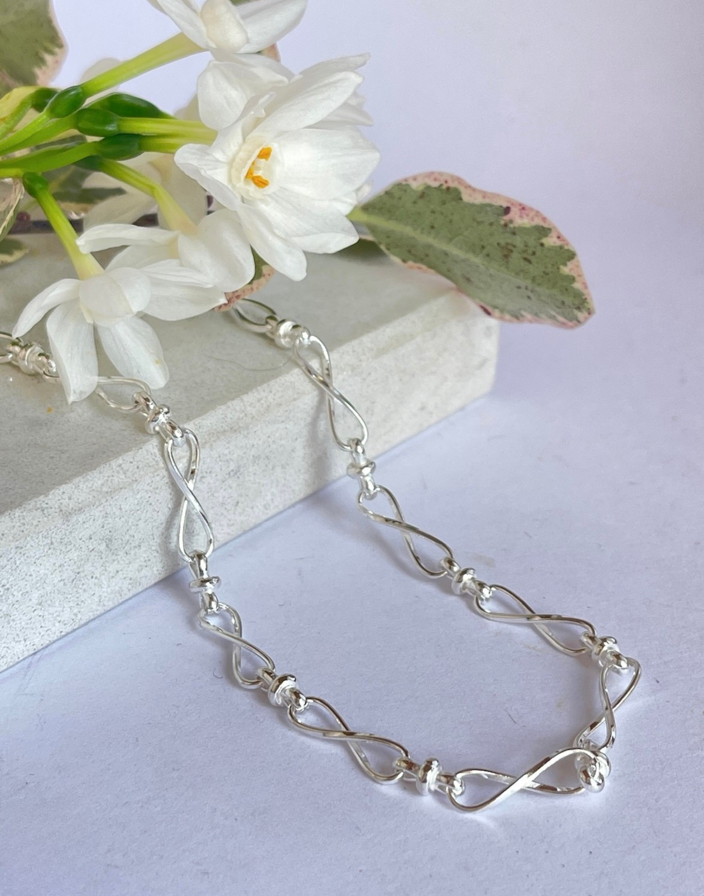 Silver Infinity Necklace on a tile