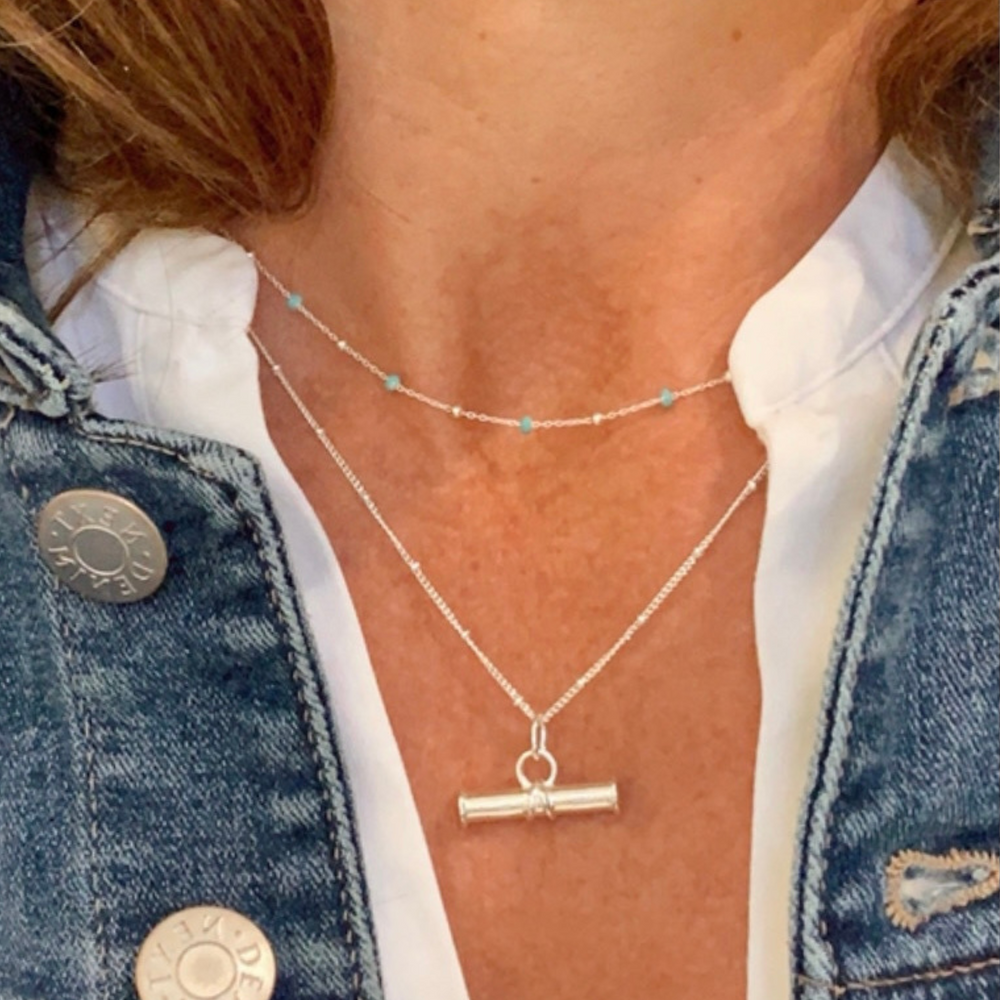 model wears light turquoise enamel necklace with silver t bar