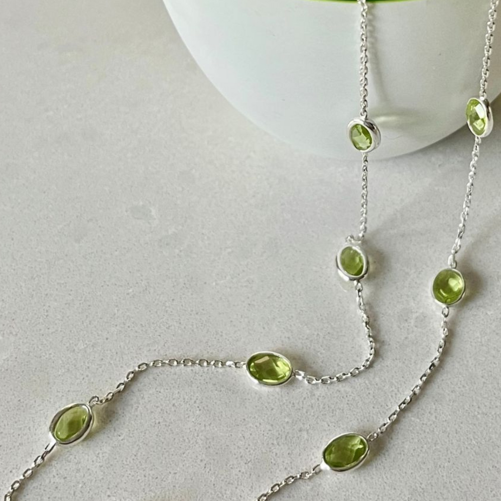 silver peridot necklace flowing from bowl