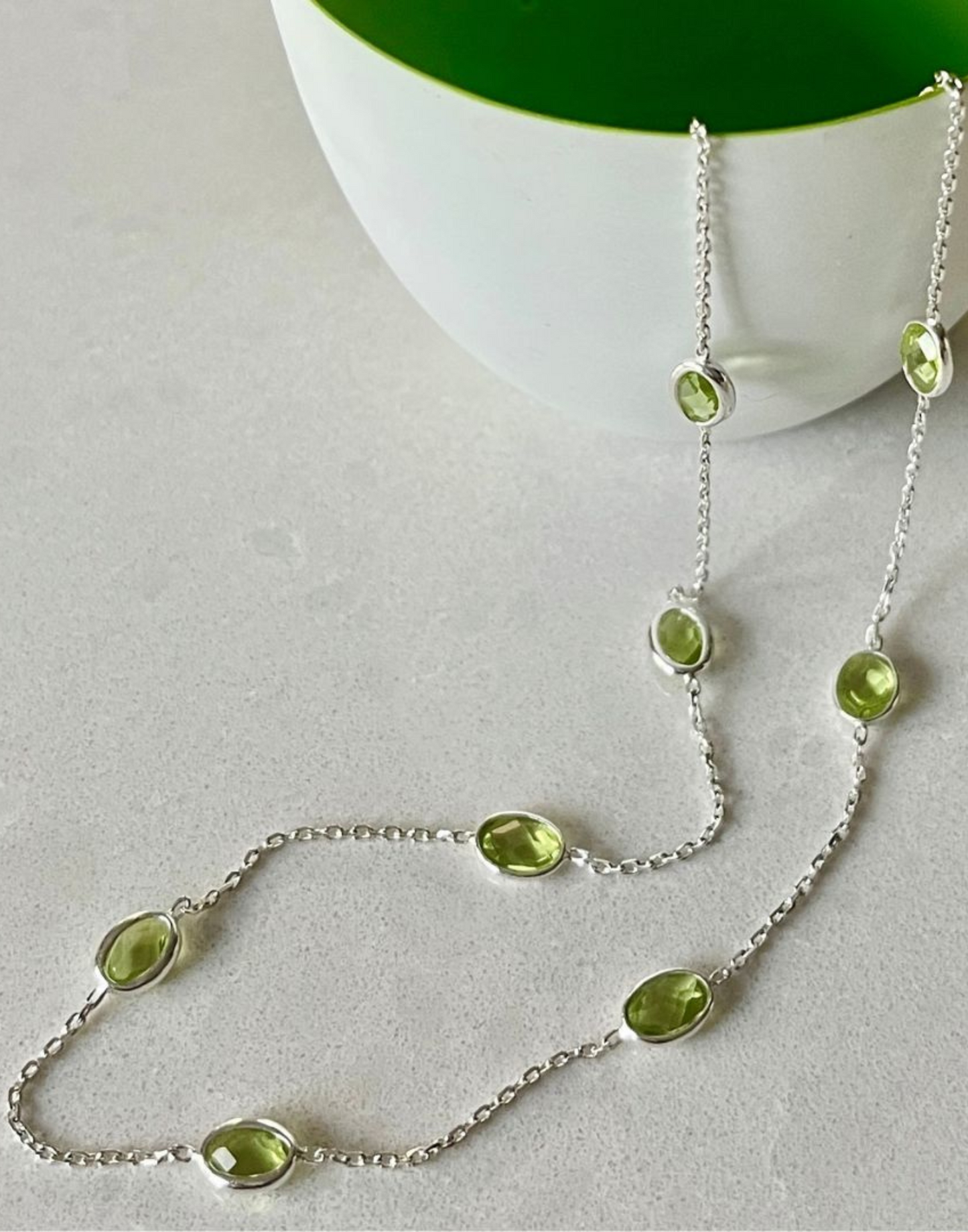 silver peridot necklace flowing from bowl