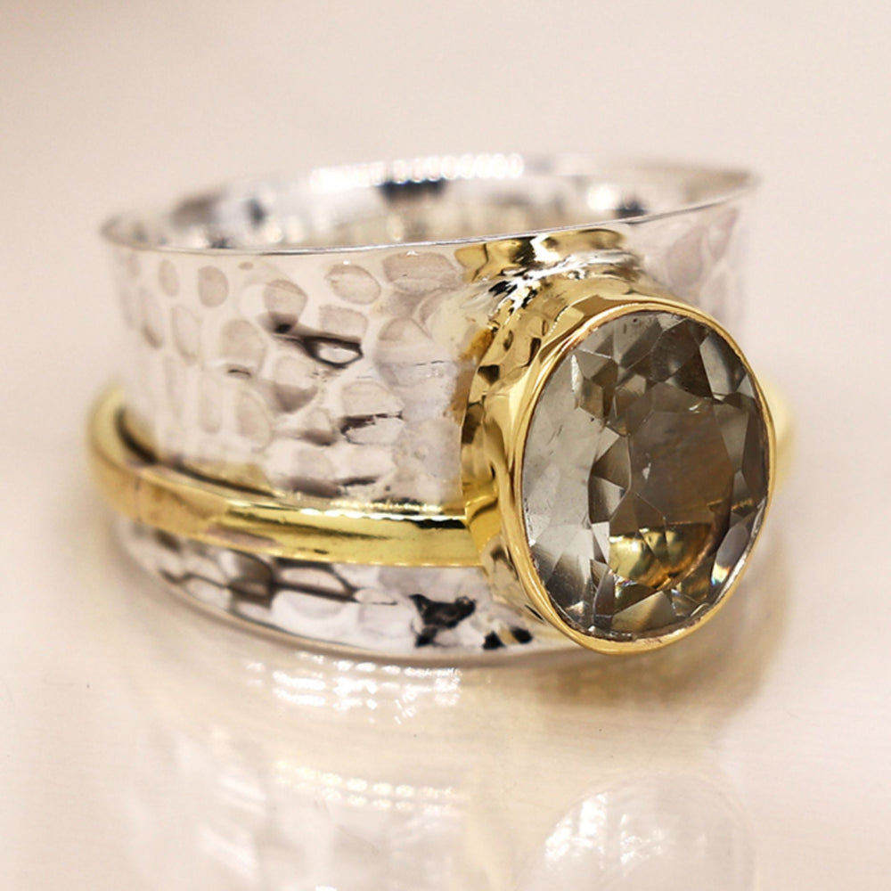 Silver spinning ring with green amethyst with a textured design on a light background