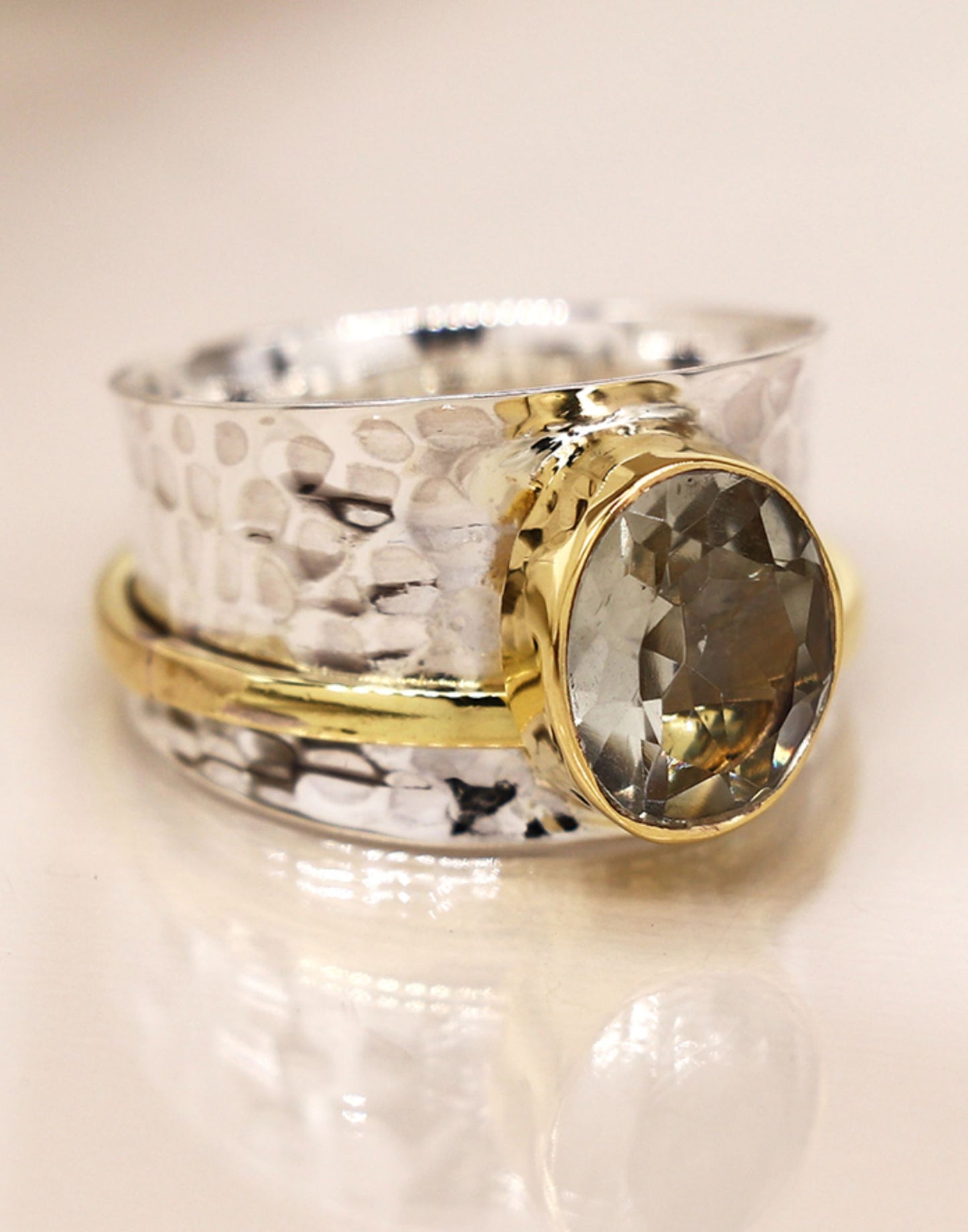 Silver spinning ring with green amethyst with a textured design on a light background