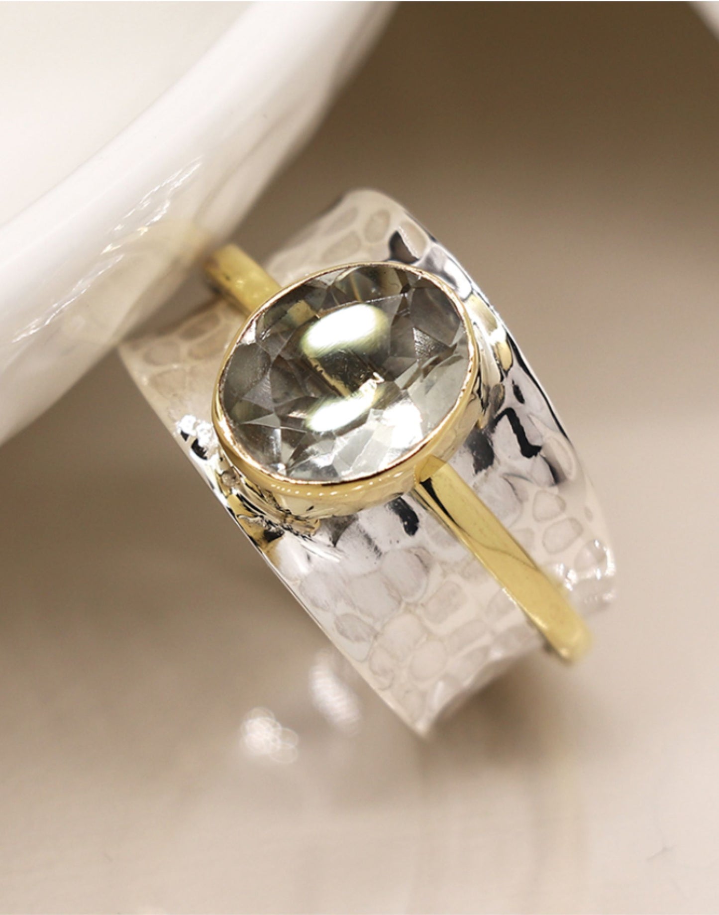 Silver spinning ring with green amethyst with a textured design on a light background