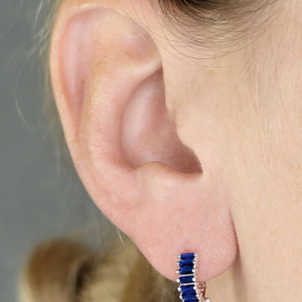 Silver and blue holiday huggie earrings on model