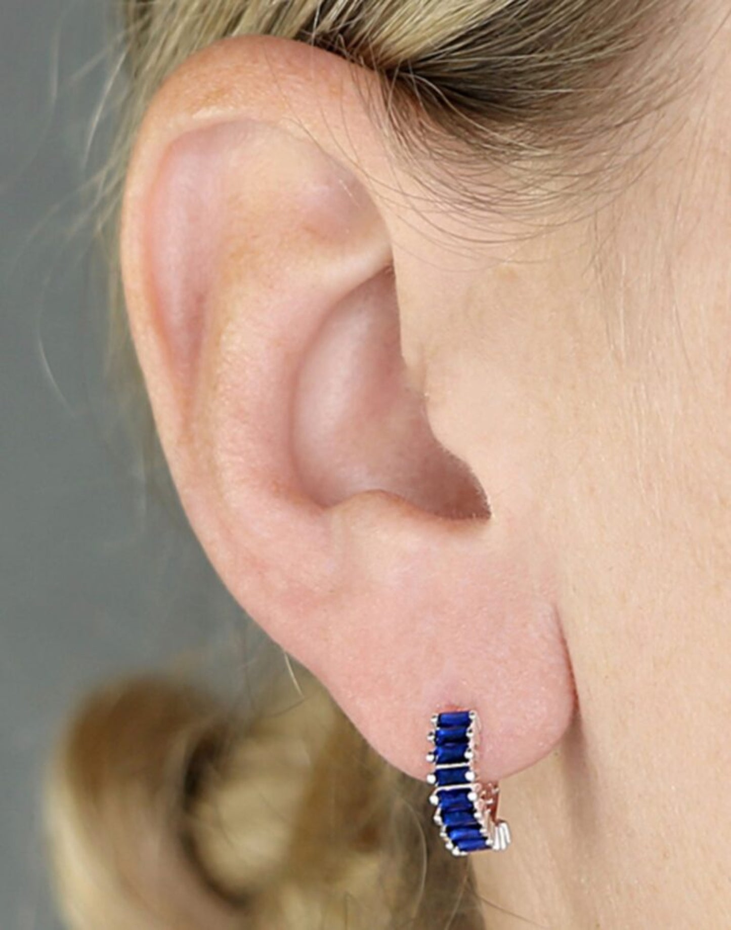 Silver and blue holiday huggie earrings on model
