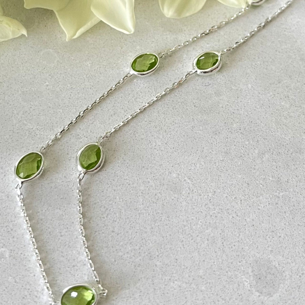 silver peridot necklace on tile