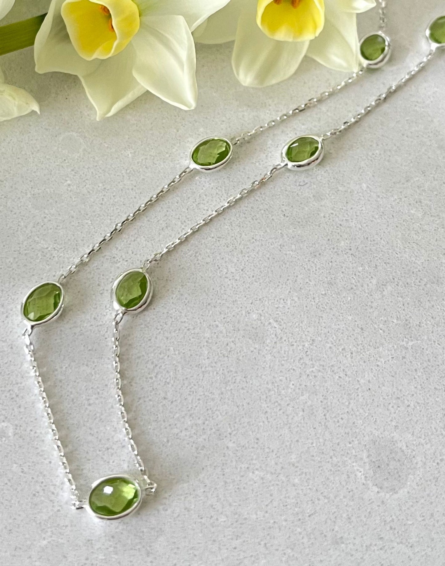 silver peridot necklace on tile