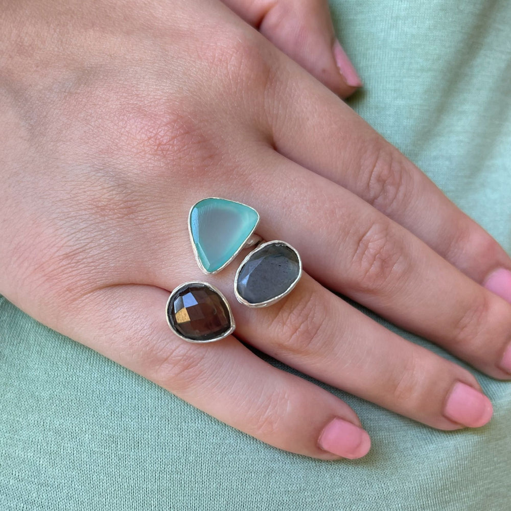 model wears a pretty stone and silver chunky ring on a light green fabric background