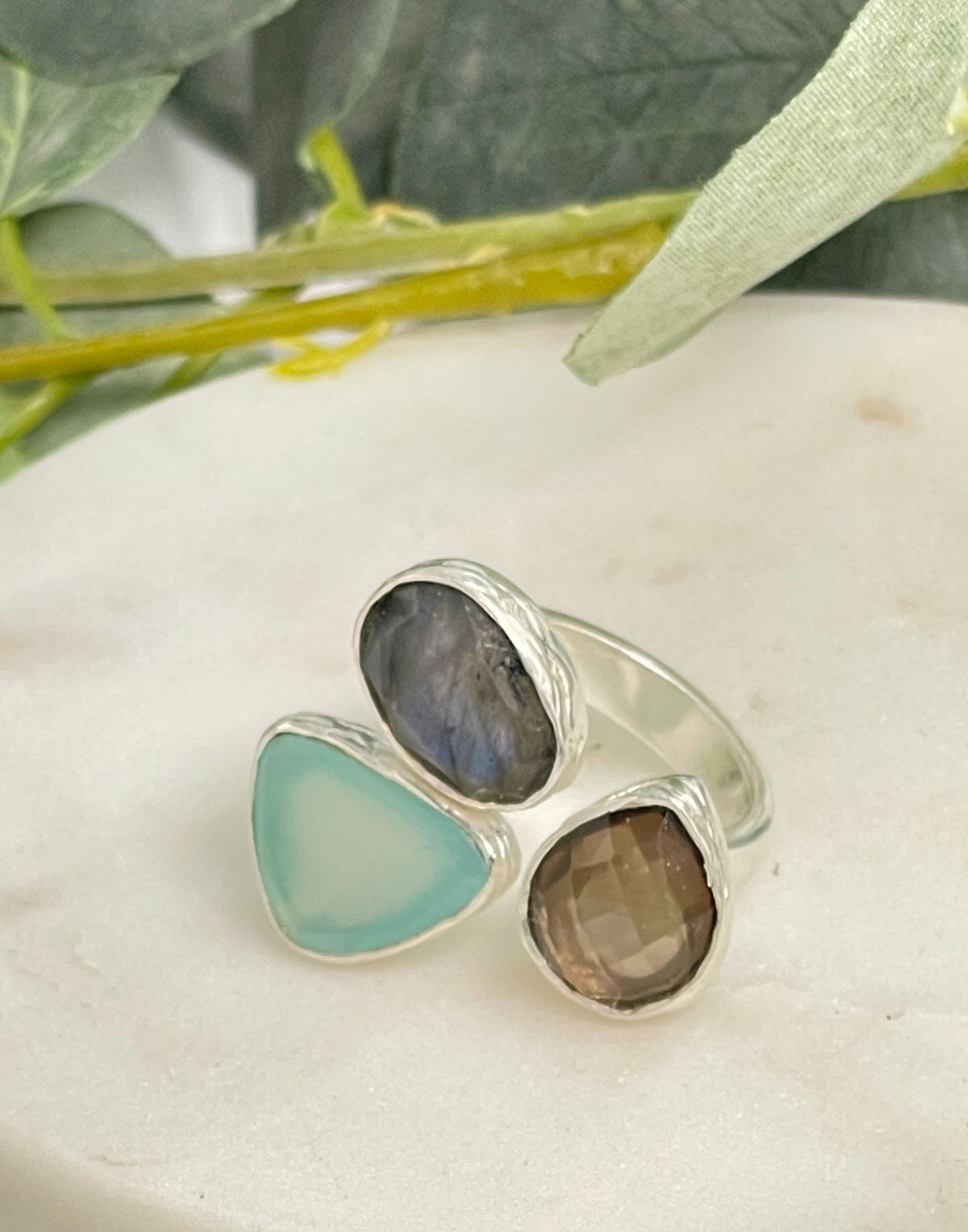 Stone and silver chunky ring on a white surface with greenery