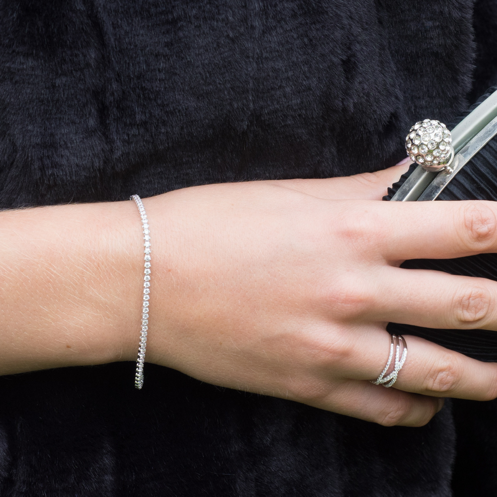 Close-up of a hand holding a handbag wearing a tania cubic zirconia silver tennis bracelet 