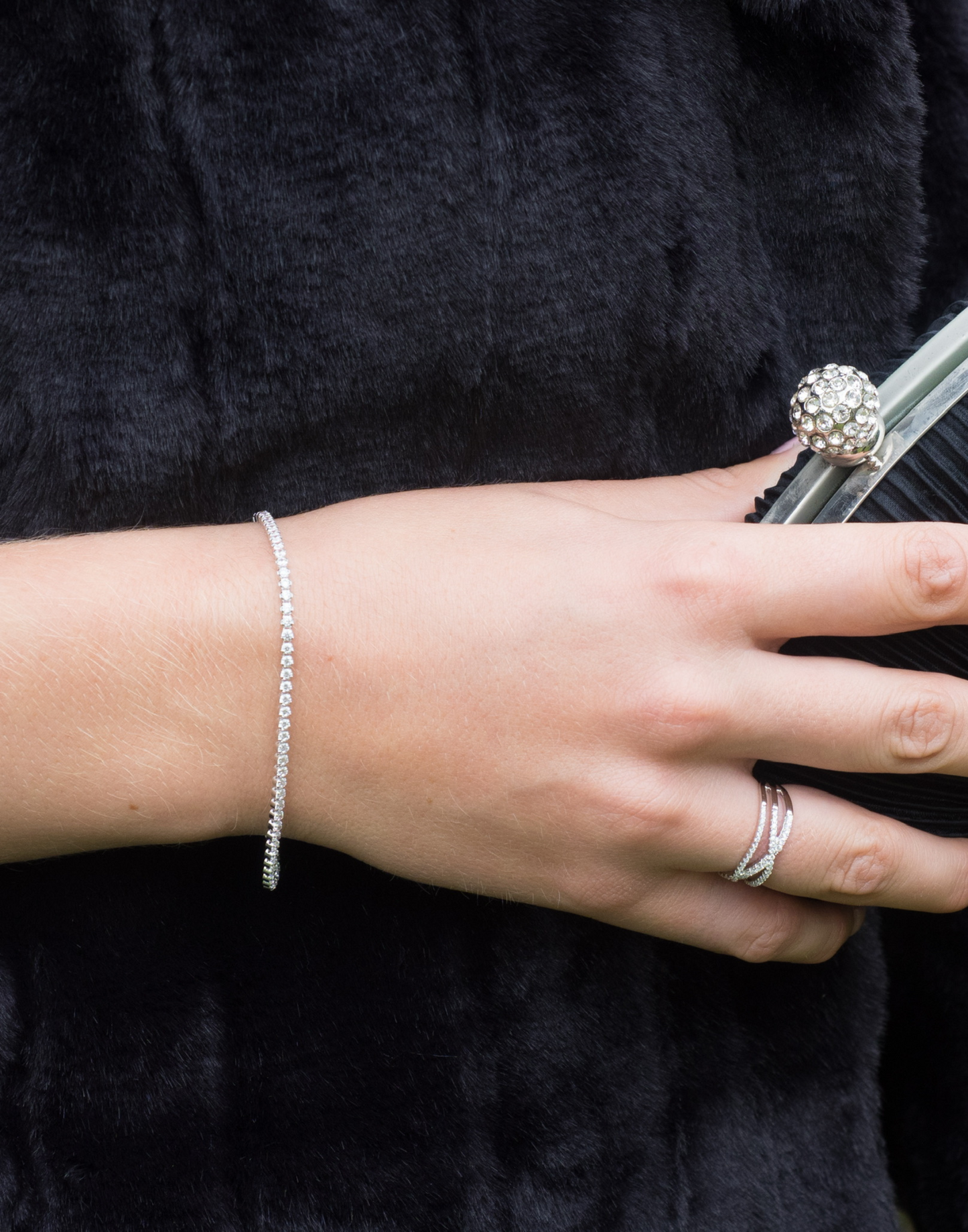Close-up of a hand holding a handbag wearing a tania cubic zirconia silver tennis bracelet 
