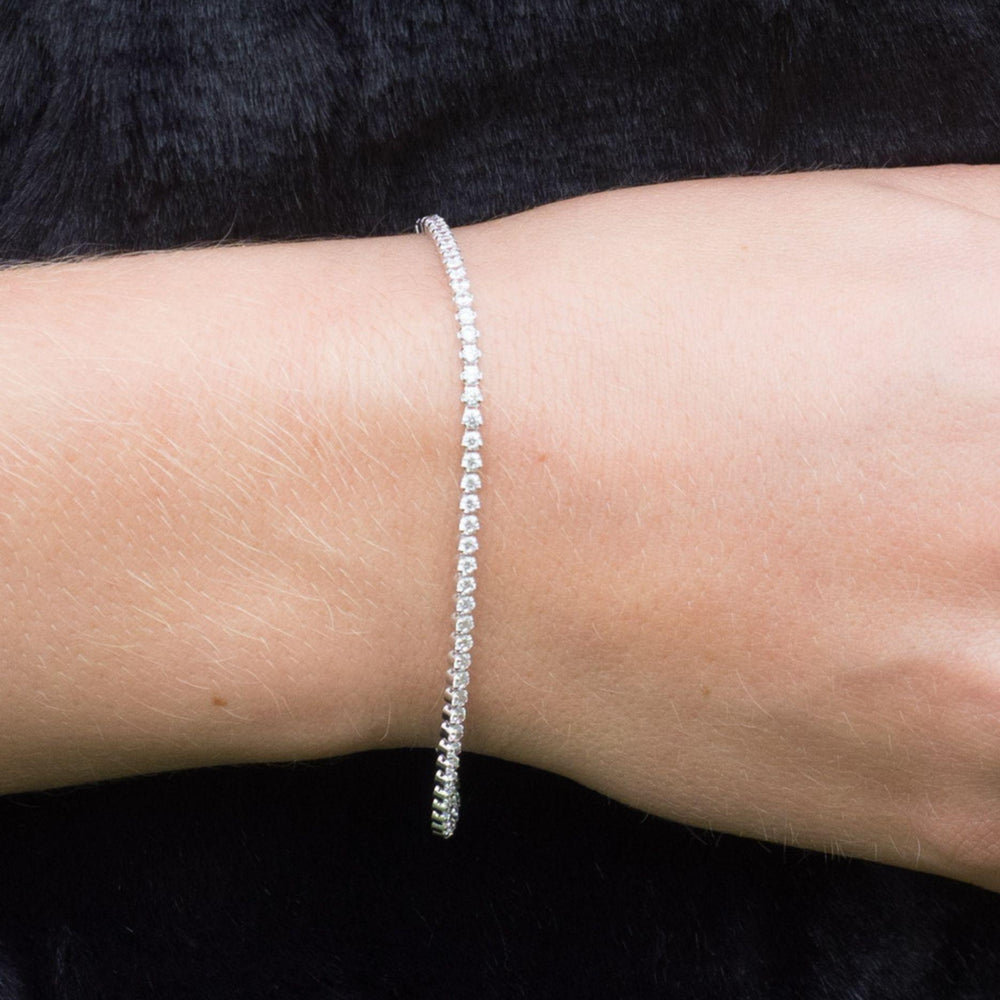 
                  
                    Close-up of a hand holding a handbag wearing a tania cubic zirconia silver tennis bracelet 
                  
                