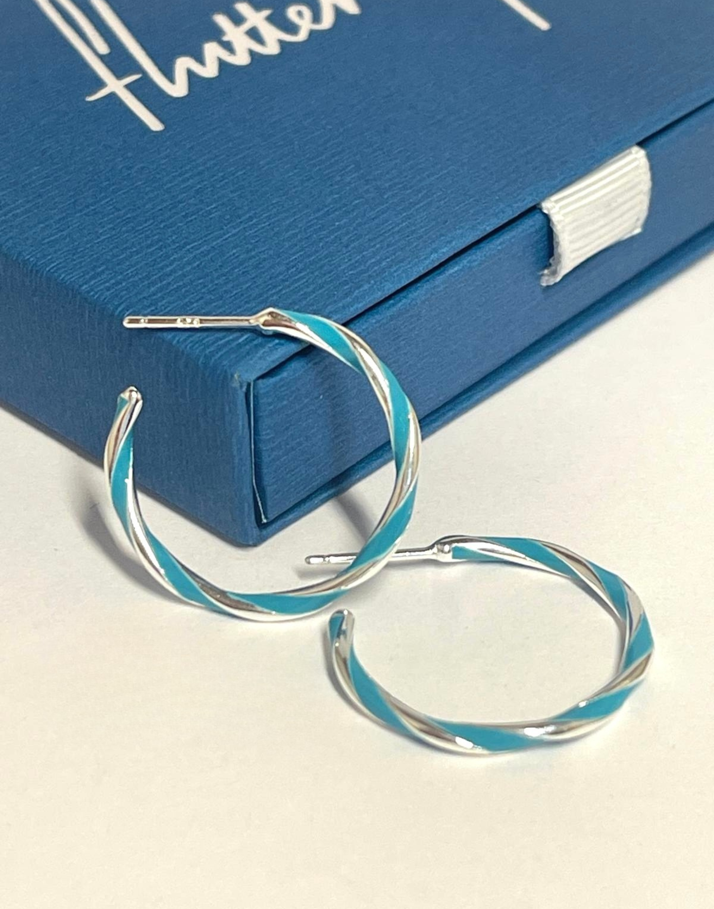 Turquoise candy stripe hoop earrings on tile