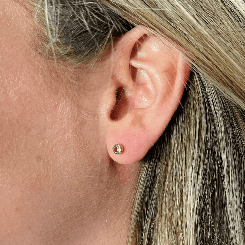 
                  
                    blue topaz coloured birthstone studs in model's ear
                  
                